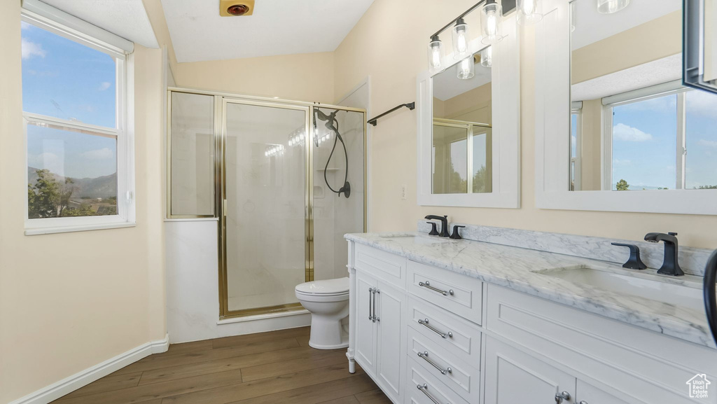 Full bath featuring wood finished floors, toilet, a stall shower, double vanity, and baseboards