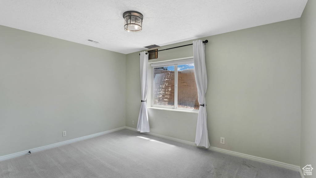 Carpeted spare room featuring baseboards