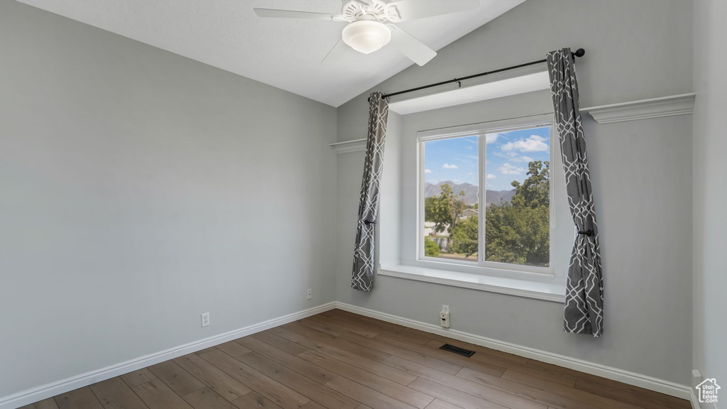 Empty room featuring vaulted ceiling, baseboards, wood finished floors, and ceiling fan