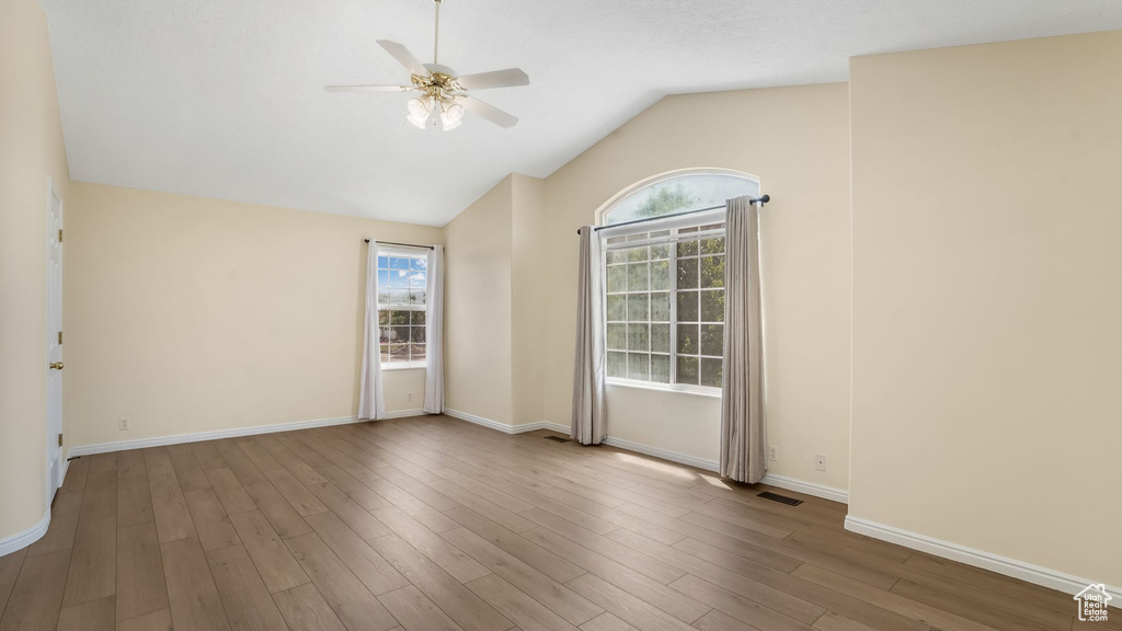 Spare room featuring a ceiling fan, lofted ceiling, wood finished floors, and baseboards