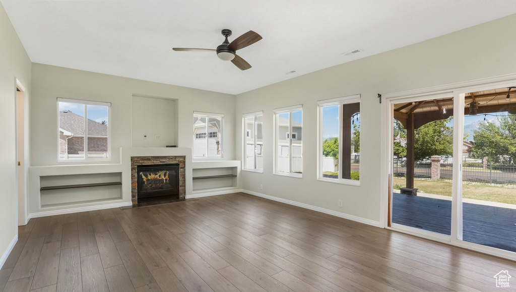 Unfurnished living room with a ceiling fan, a fireplace, dark wood finished floors, baseboards, and built in features