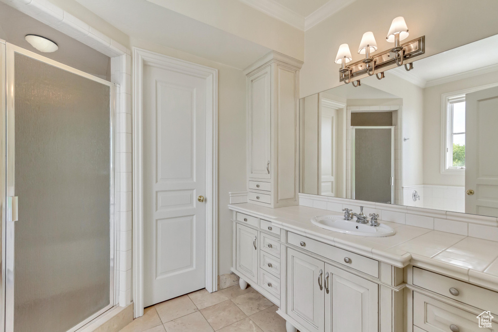 Bathroom featuring tile patterned floors, vanity, a shower with door, and ornamental molding