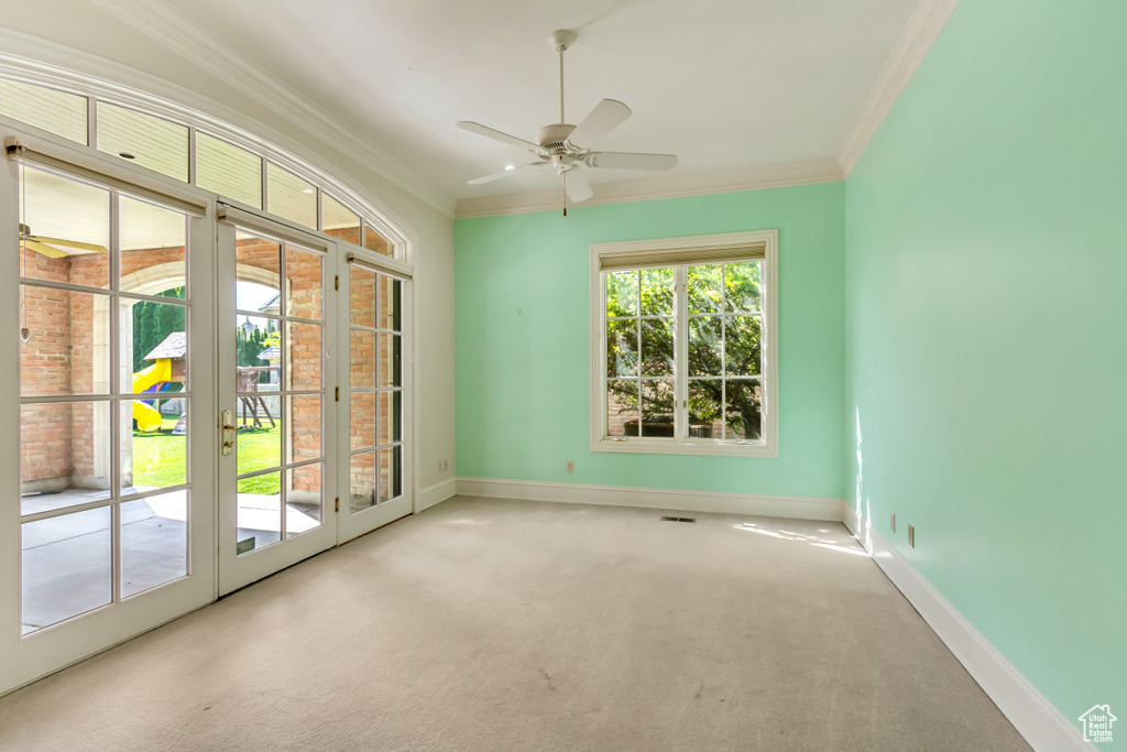 Carpeted empty room with french doors, crown molding, and ceiling fan