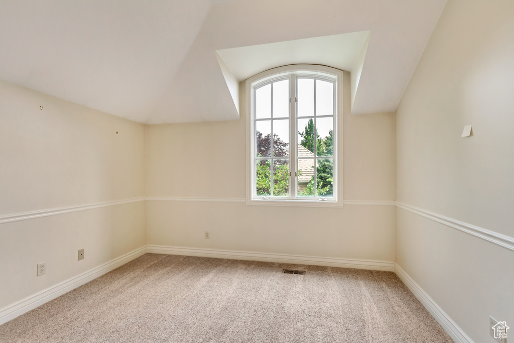 Bonus room with vaulted ceiling and light colored carpet