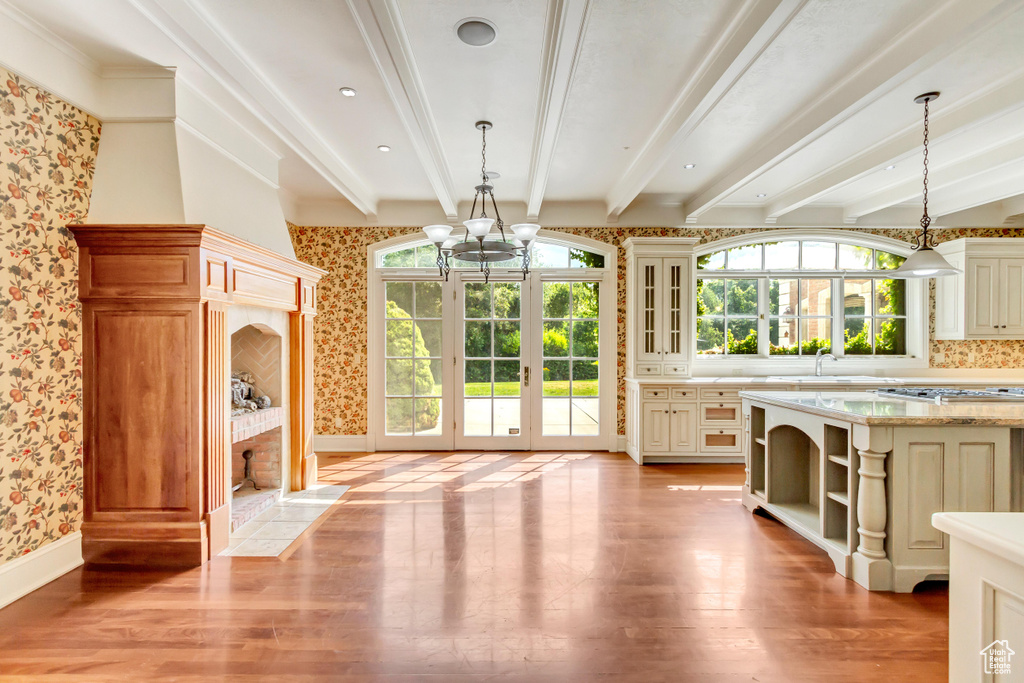 Interior space featuring beam ceiling, light hardwood / wood-style floors, a chandelier, and a healthy amount of sunlight