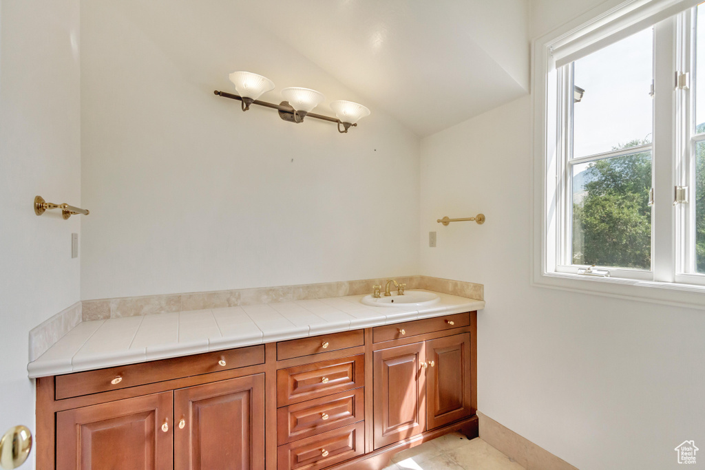 Bathroom featuring tile patterned floors, vanity, and vaulted ceiling