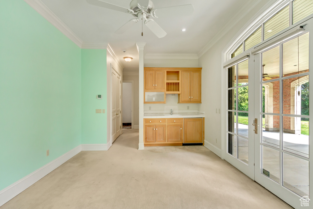 Unfurnished living room with ceiling fan, sink, light carpet, and crown molding