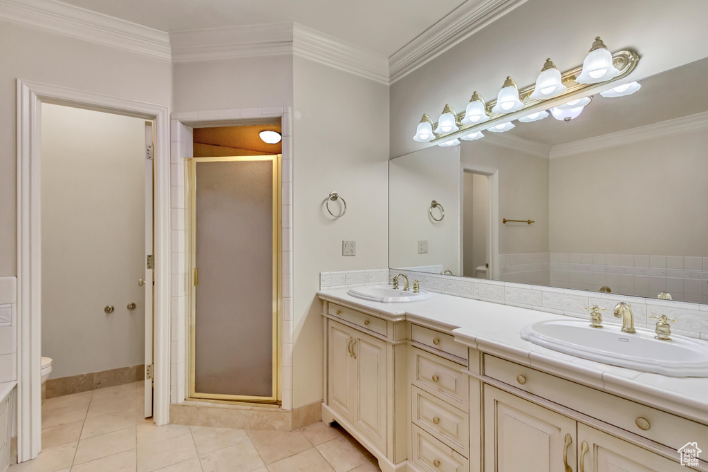 Bathroom featuring walk in shower, toilet, crown molding, tile patterned floors, and dual vanity