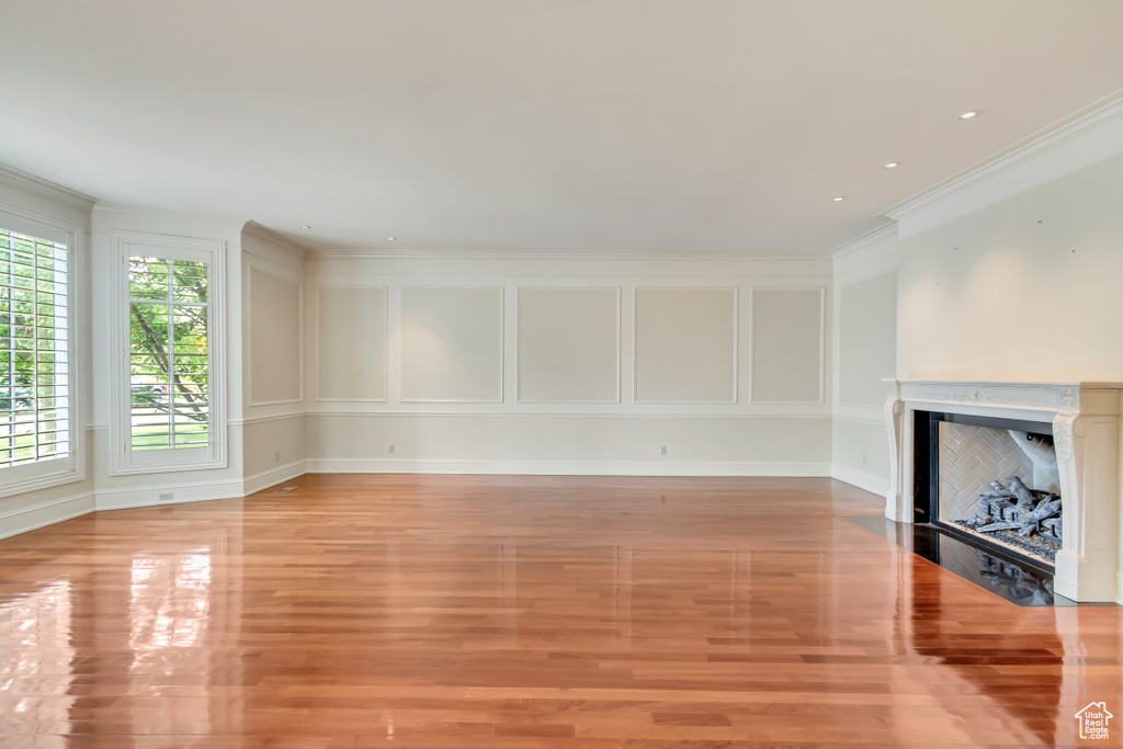 Unfurnished living room featuring ornamental molding and light hardwood / wood-style floors