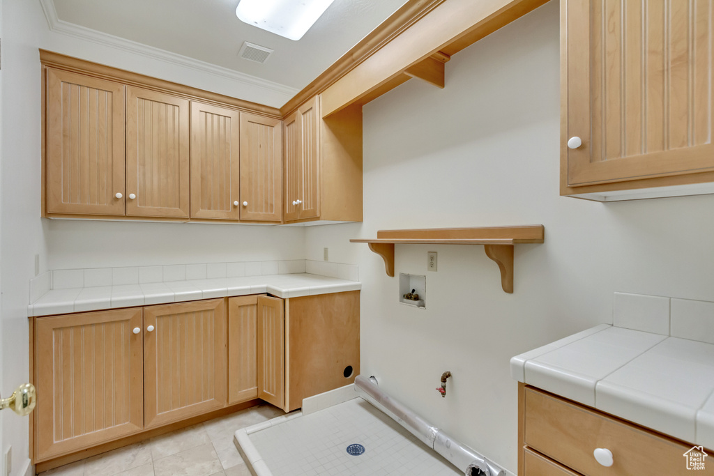 Laundry room with gas dryer hookup, cabinets, crown molding, washer hookup, and light tile patterned floors