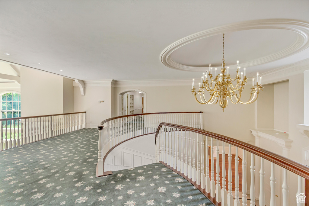Corridor with a tray ceiling, an inviting chandelier, and carpet floors