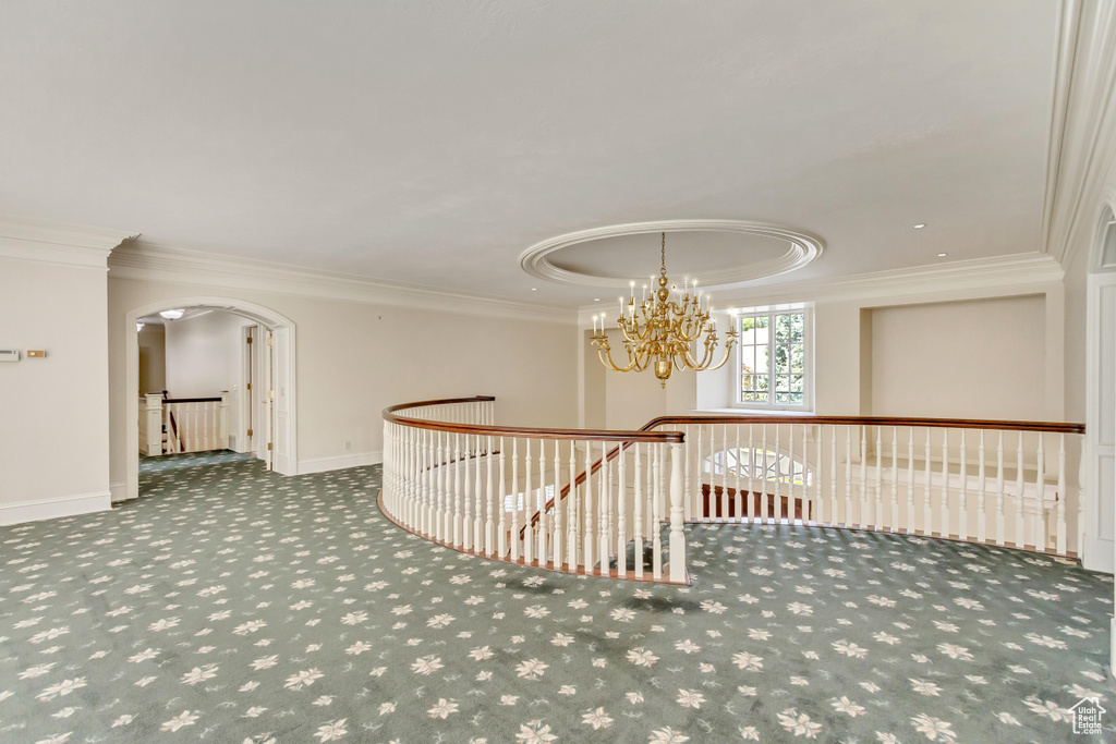 Hall featuring carpet, ornamental molding, an inviting chandelier, and a raised ceiling