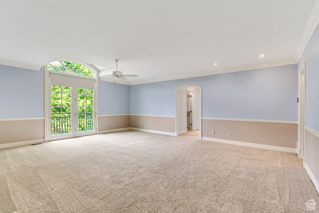 Carpeted spare room with ceiling fan and ornamental molding