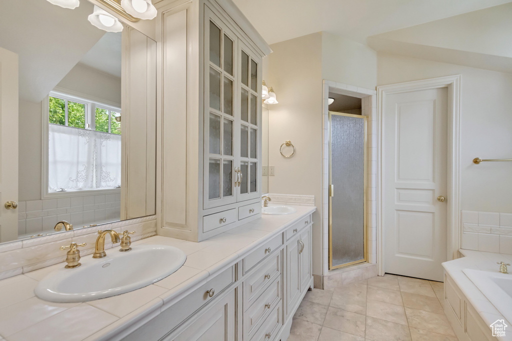 Bathroom featuring tile patterned floors, dual bowl vanity, and plus walk in shower
