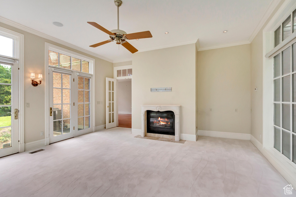 Unfurnished living room featuring ceiling fan, french doors, ornamental molding, and plenty of natural light