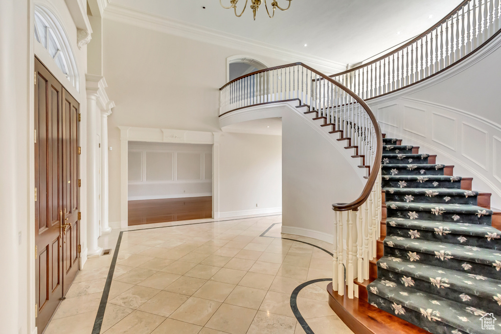 Entrance foyer with a towering ceiling, light wood-type flooring, and ornamental molding