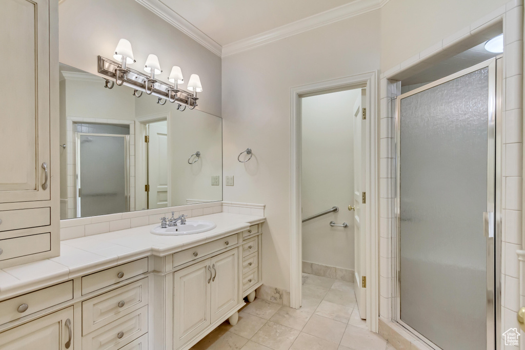 Bathroom with a shower with door, ornamental molding, tile patterned floors, and vanity