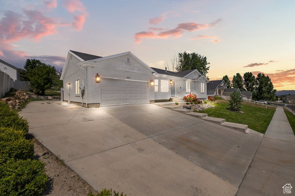 Ranch-style home with a garage, driveway, and stucco siding