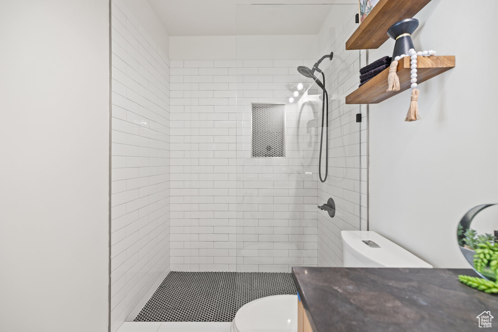 Full bath featuring toilet, a tile shower, and vanity