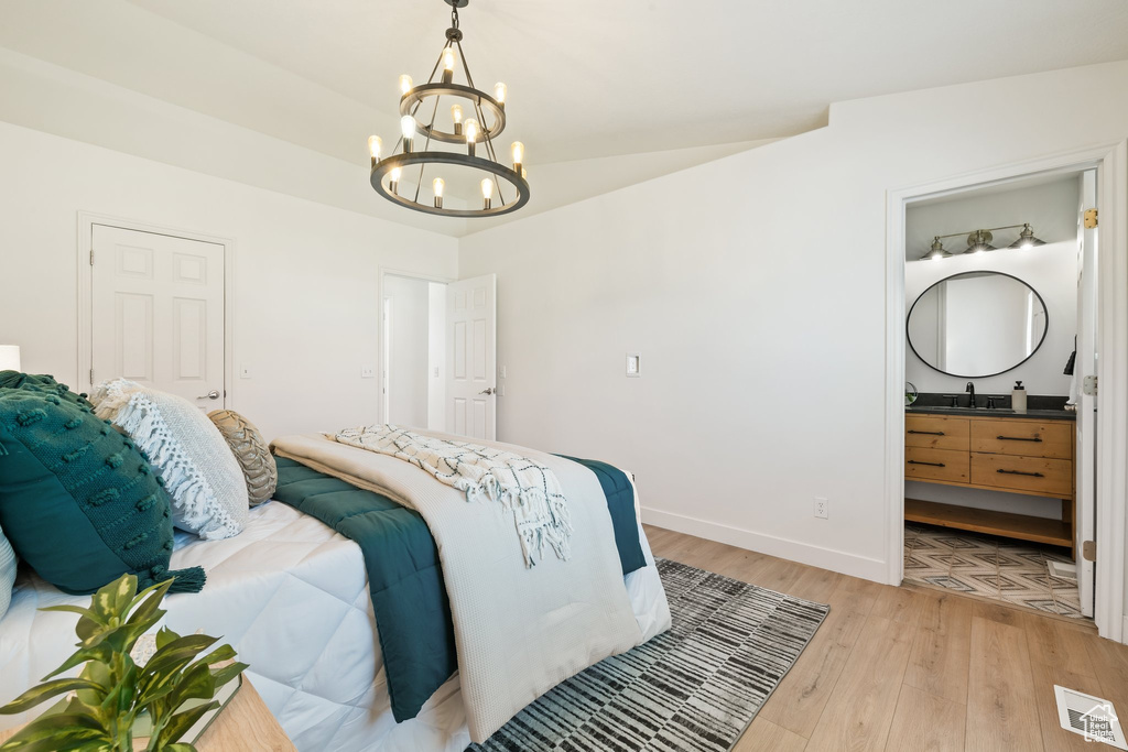 Bedroom featuring a chandelier, light wood-type flooring, baseboards, connected bathroom, and lofted ceiling