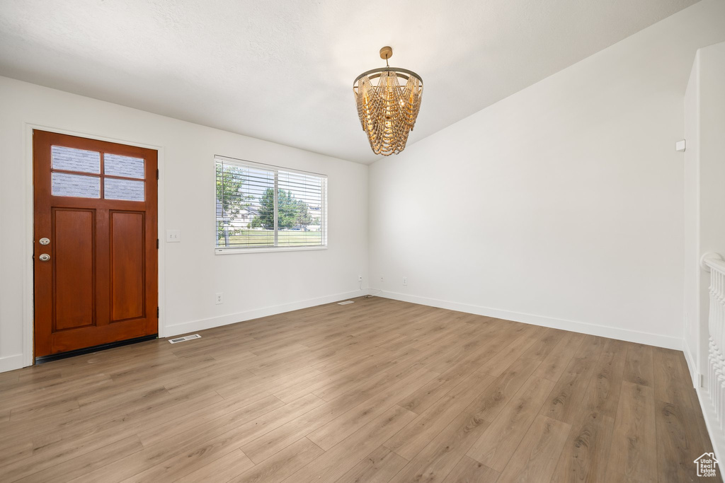 Entrance foyer with a chandelier, light wood finished floors, and baseboards