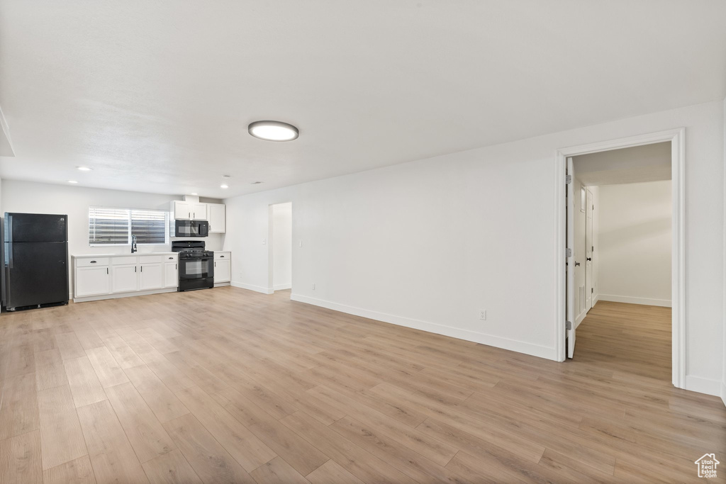 Unfurnished living room featuring light wood-style floors, baseboards, and recessed lighting
