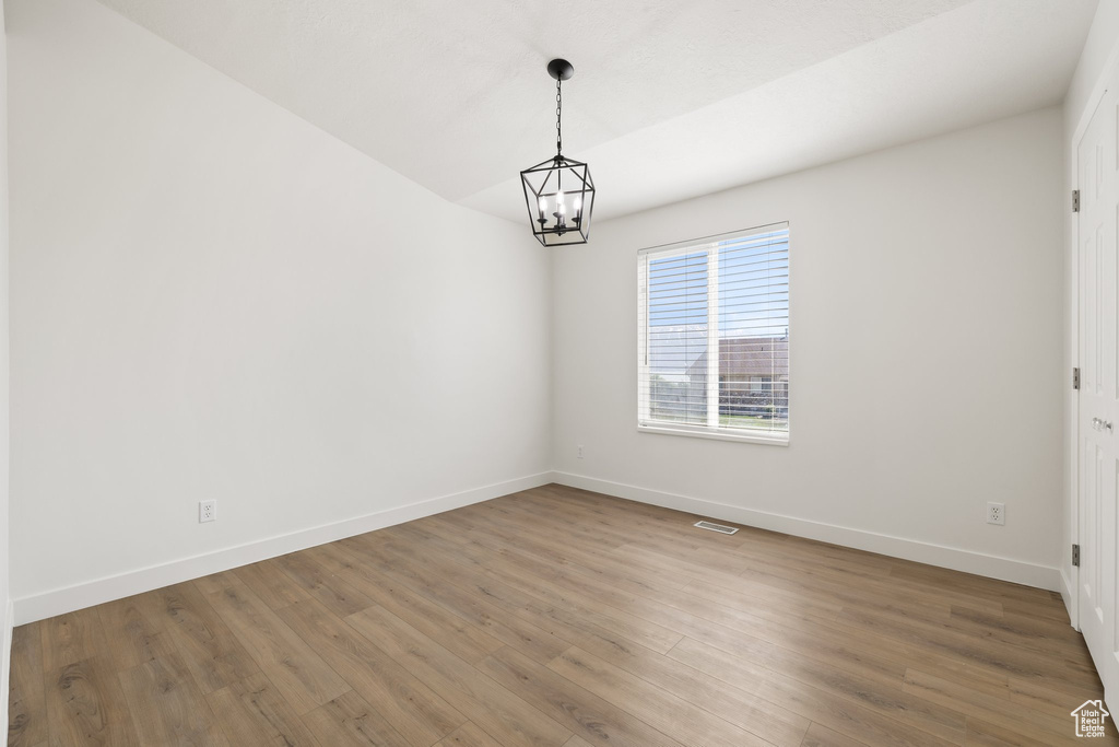 Unfurnished room with a chandelier, baseboards, and wood finished floors