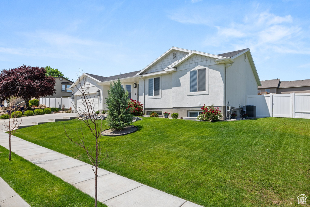 Ranch-style home with central air condition unit, a garage, and stucco siding