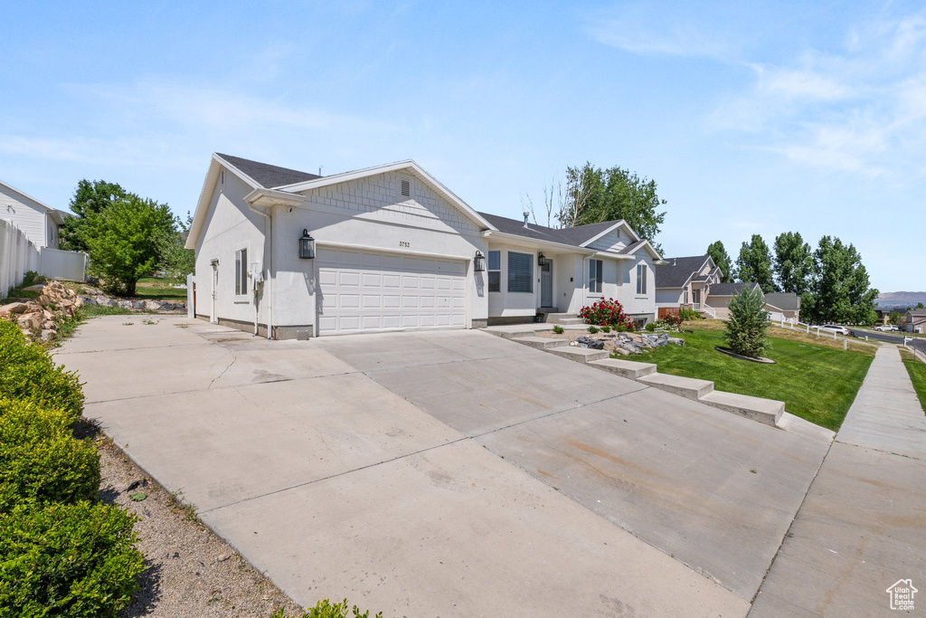 Ranch-style house featuring an attached garage, driveway, and stucco siding