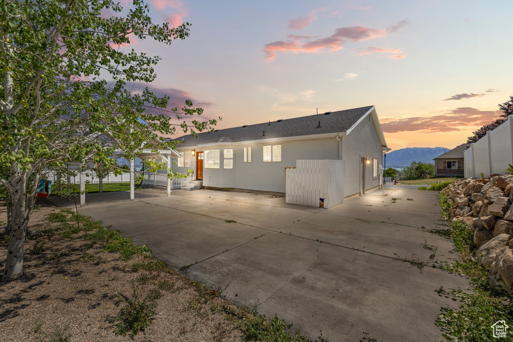 Back of house at dusk featuring a patio area and stucco siding