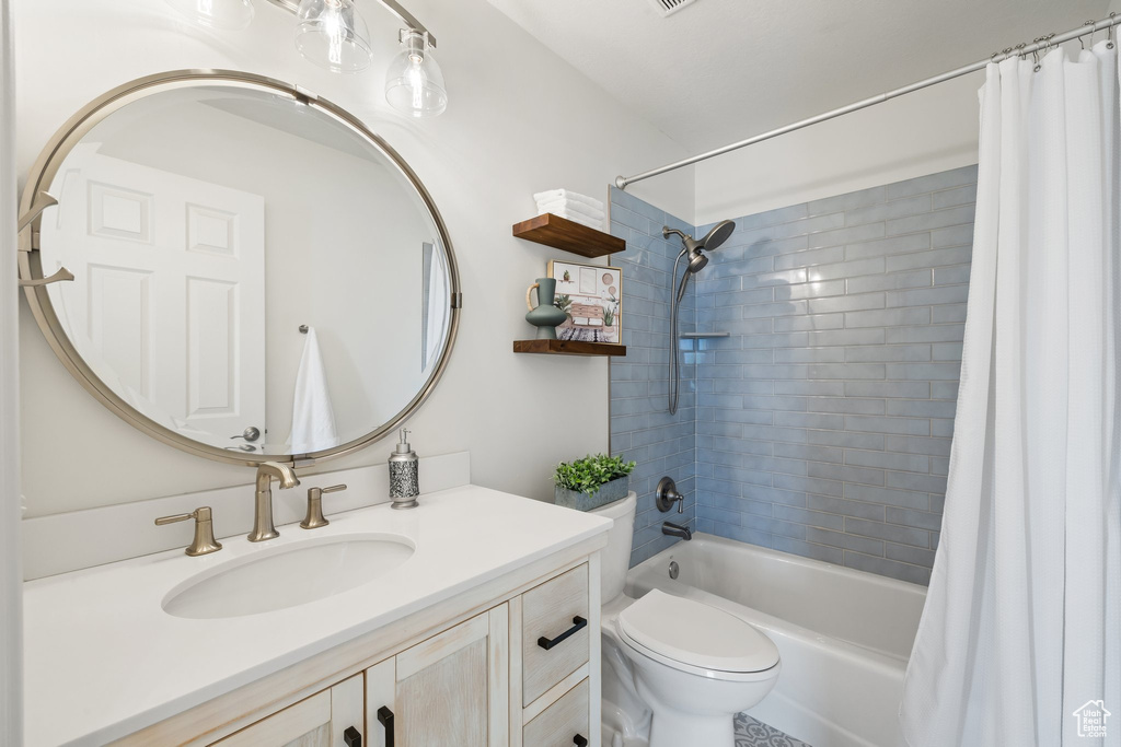 Bathroom with vanity, shower / bath combo, and toilet