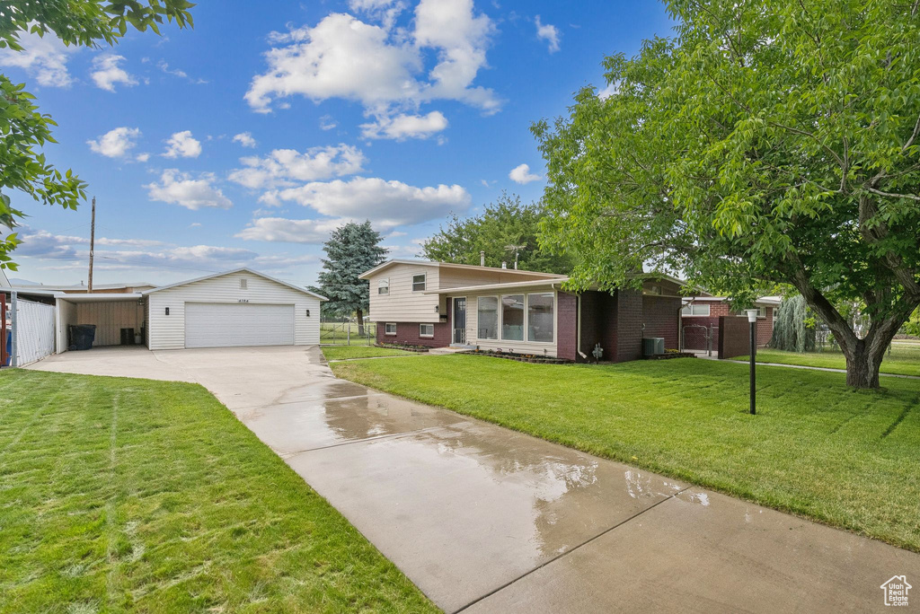 Split level home with brick siding, an outbuilding, and a garage