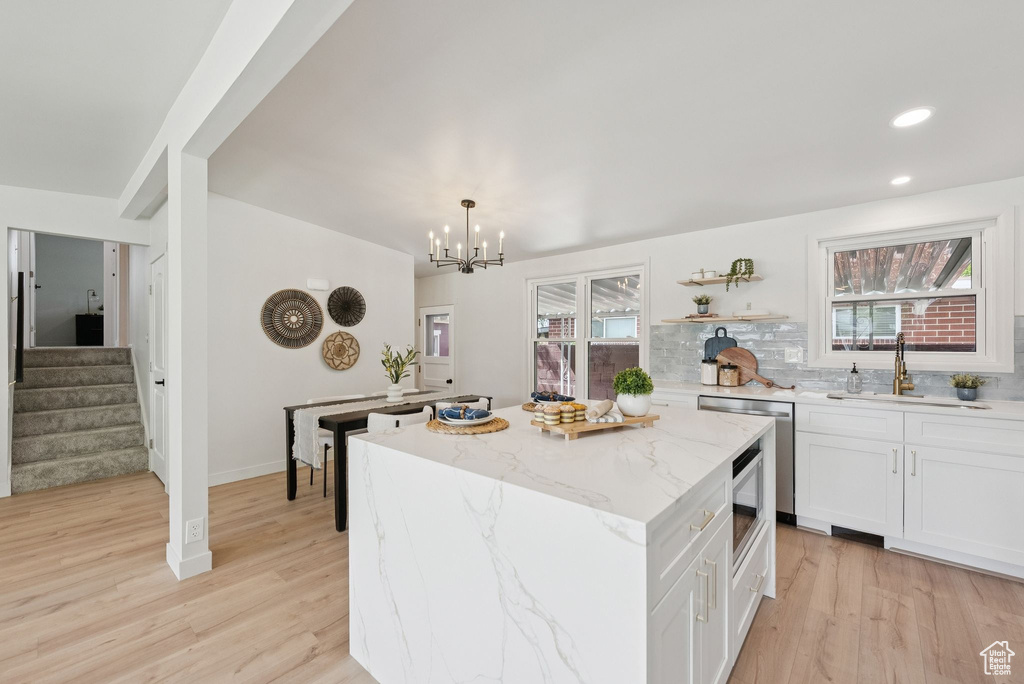 Kitchen featuring a sink, a center island, light wood-type flooring, a chandelier, and recessed lighting