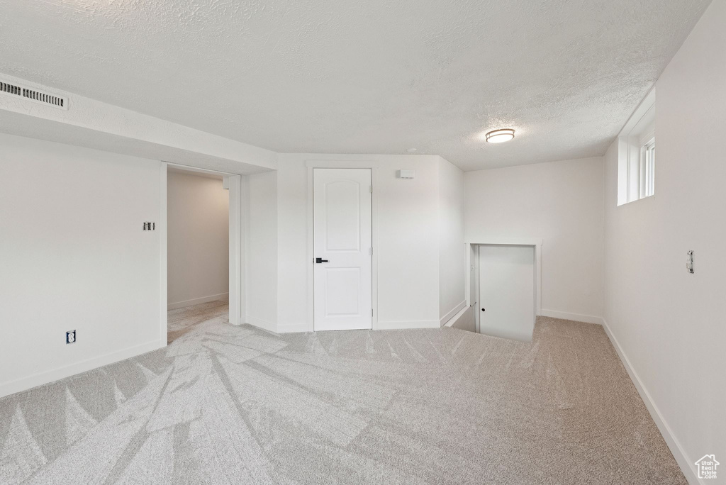 Below grade area with a textured ceiling, carpet flooring, and baseboards
