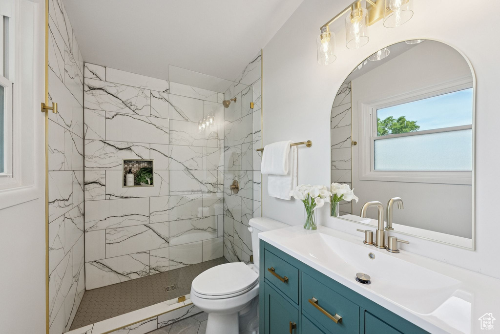 Bathroom featuring toilet, vanity, and a marble finish shower