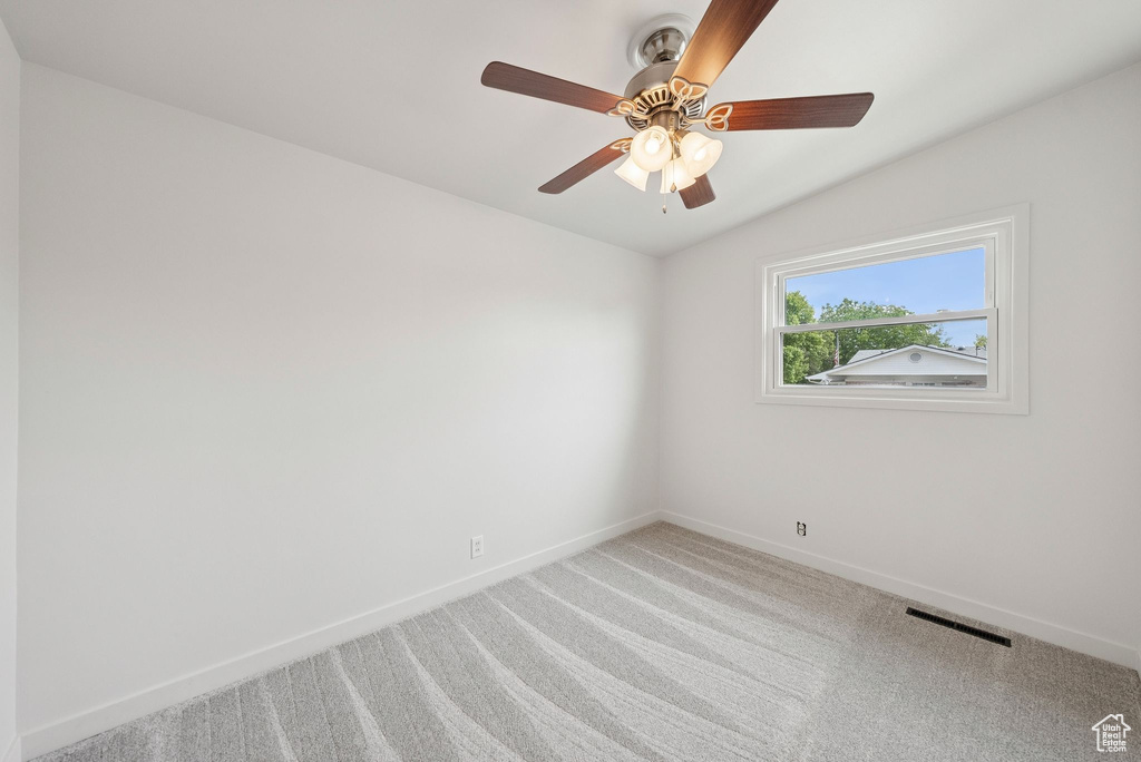 Carpeted spare room with baseboards, ceiling fan, and vaulted ceiling