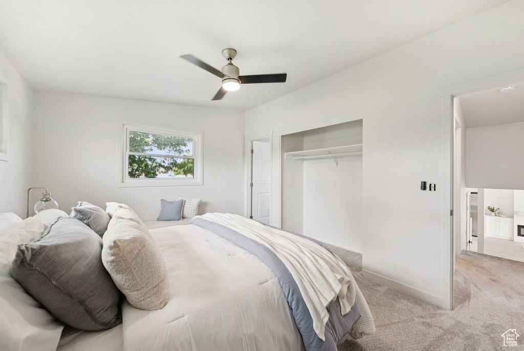 Bedroom featuring light colored carpet, a closet, baseboards, and ceiling fan