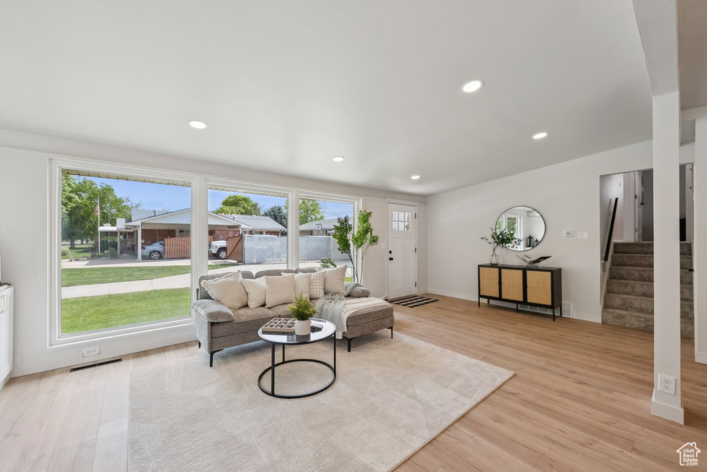 Living room with light wood finished floors, stairs, and recessed lighting