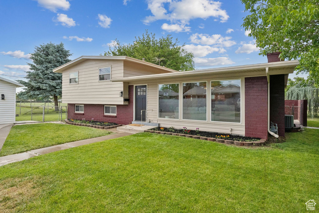 Tri-level home with central air condition unit, brick siding, and a chimney