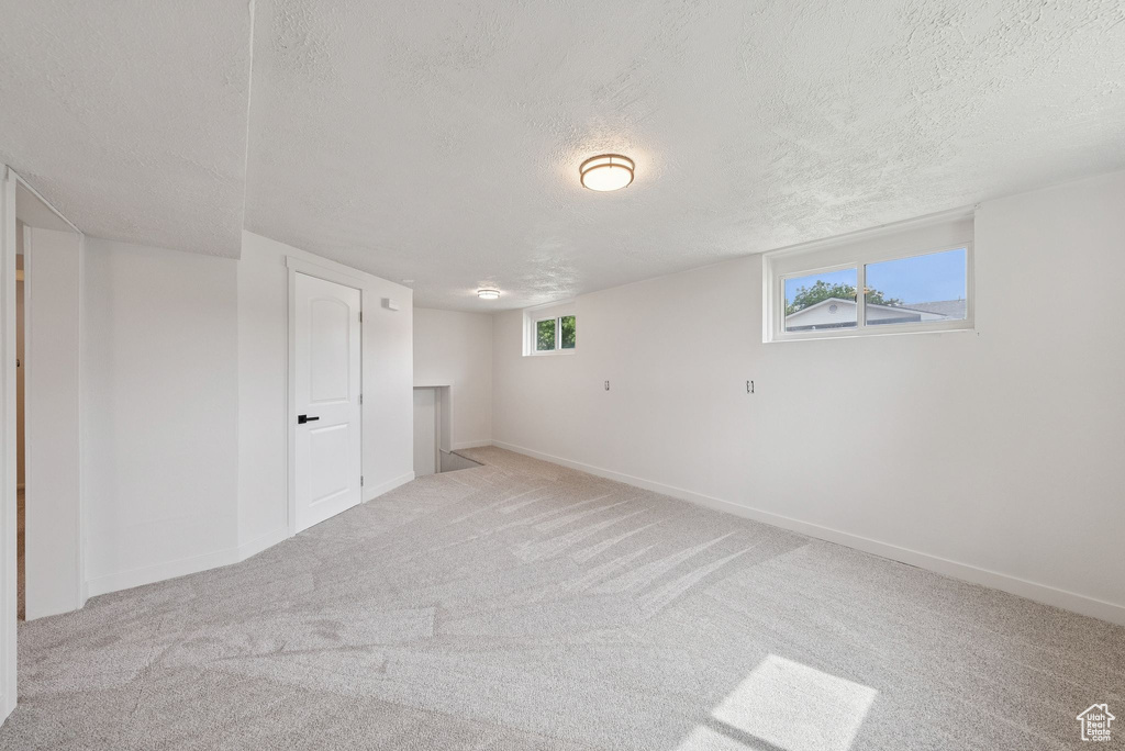 Basement with a textured ceiling, carpet floors, and baseboards