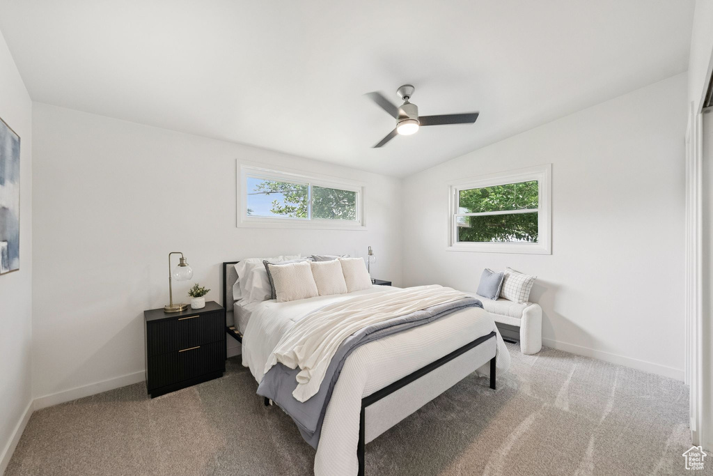 Carpeted bedroom featuring lofted ceiling, multiple windows, baseboards, and a ceiling fan