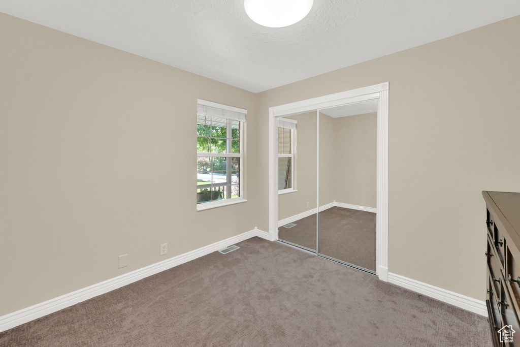 Unfurnished bedroom with carpet flooring, baseboards, a closet, and a textured ceiling