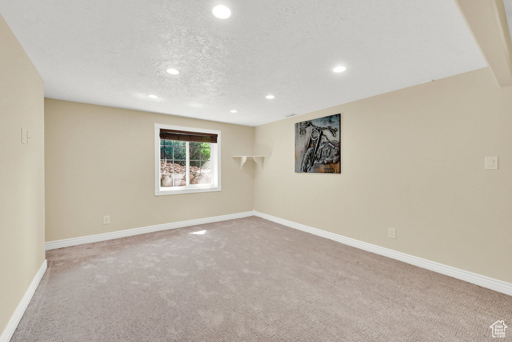 Empty room with a textured ceiling, carpet floors, recessed lighting, and baseboards