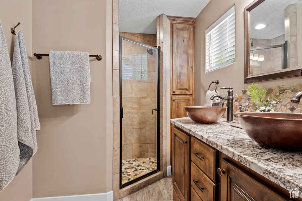 Bathroom featuring a stall shower and double vanity