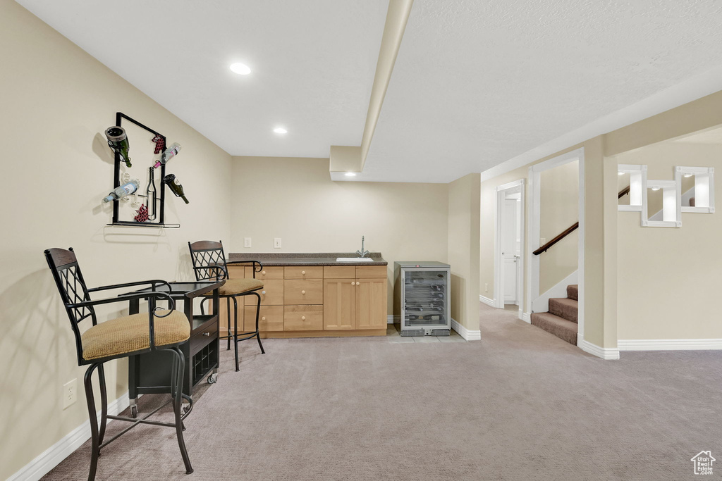 Indoor wet bar with beverage cooler, light carpet, stairway, baseboards, and recessed lighting