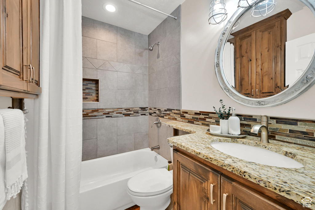 Full bathroom featuring shower / bath combo with shower curtain, vanity, backsplash, and toilet