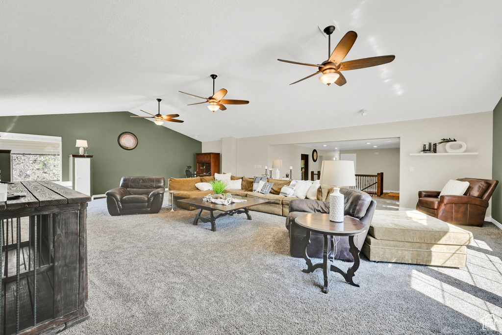 Carpeted living area featuring lofted ceiling, ceiling fan, and baseboards