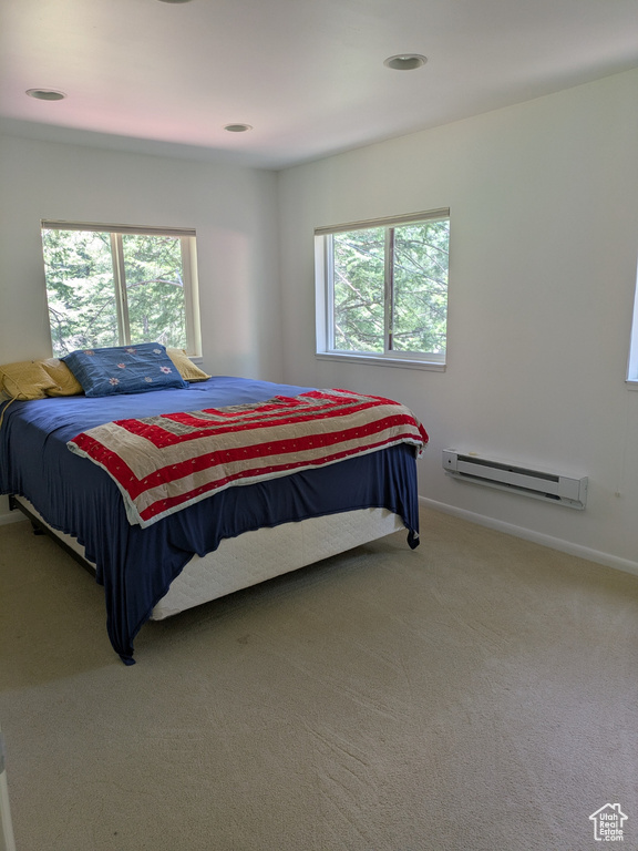 Bedroom with a baseboard radiator, multiple windows, carpet floors, and baseboards