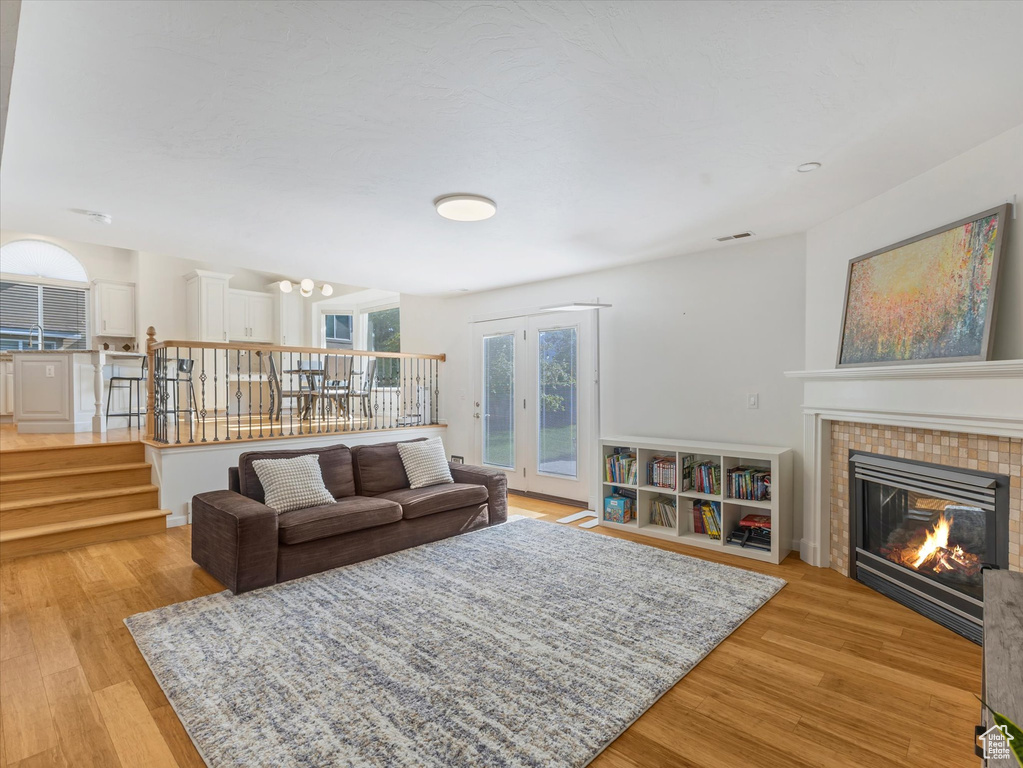 Living room featuring light wood-type flooring, a tile fireplace, a chandelier, and stairs