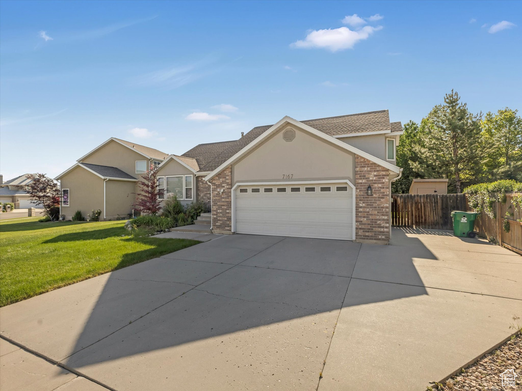 Traditional home featuring concrete driveway, brick siding, an attached garage, and stucco siding